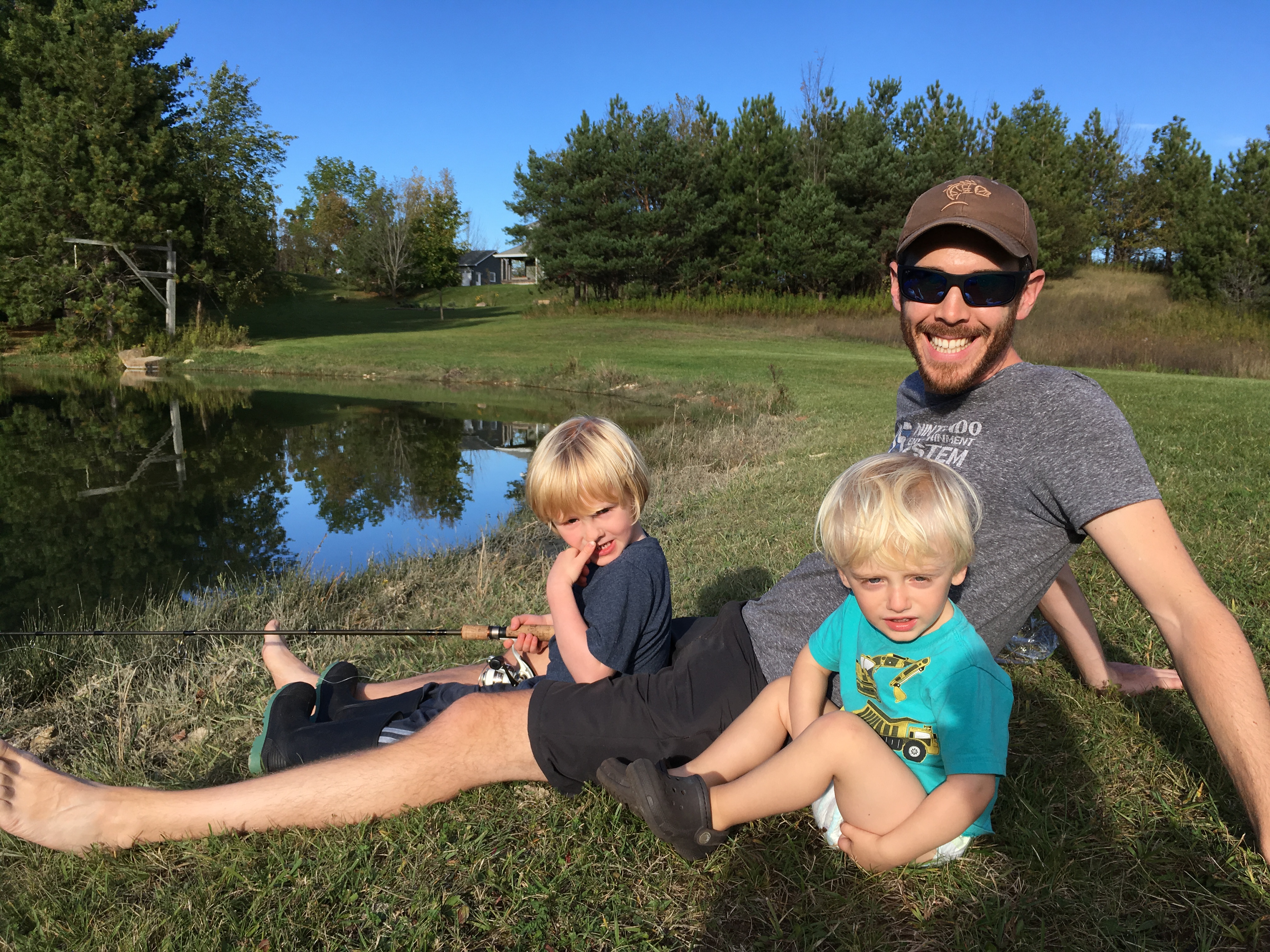 Matthew Randall fishing for rainbow trout in a small pond with his two blonde nephews.