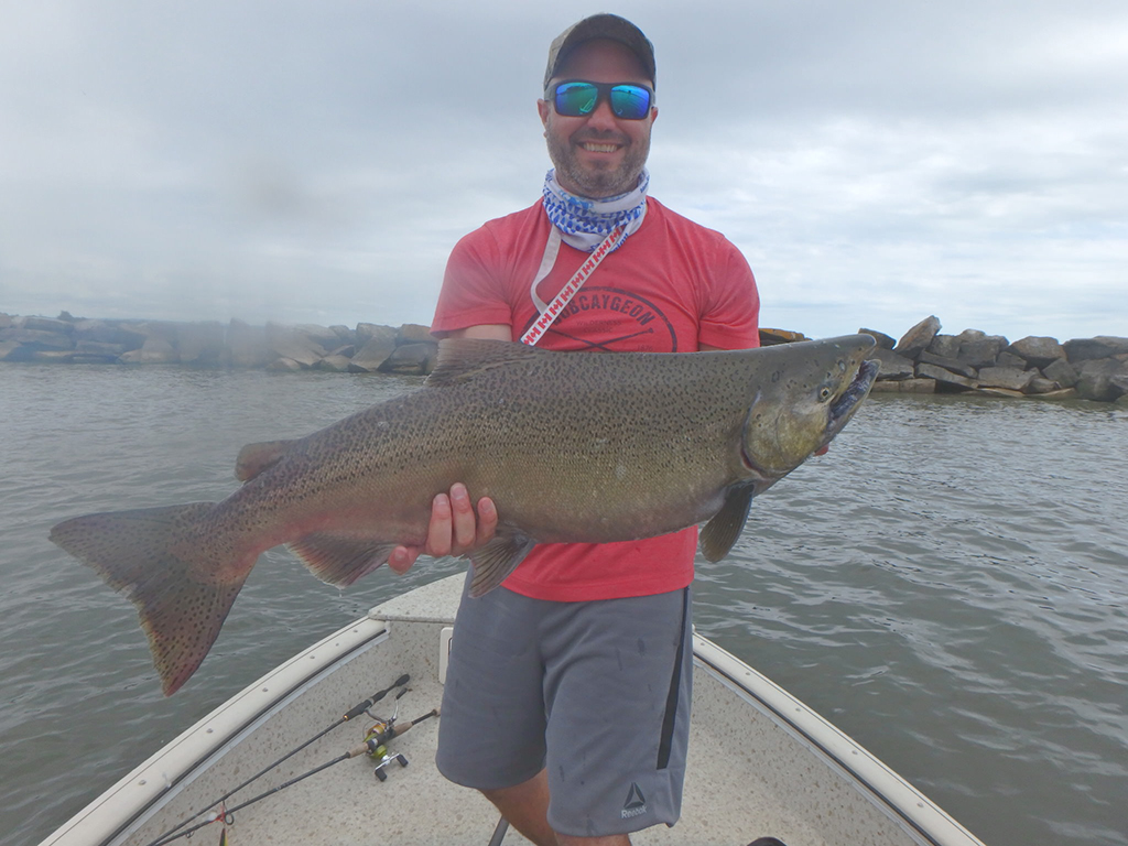 Matthew Randall's co-worker holding a big Lake Ontario Salmon in a boat.