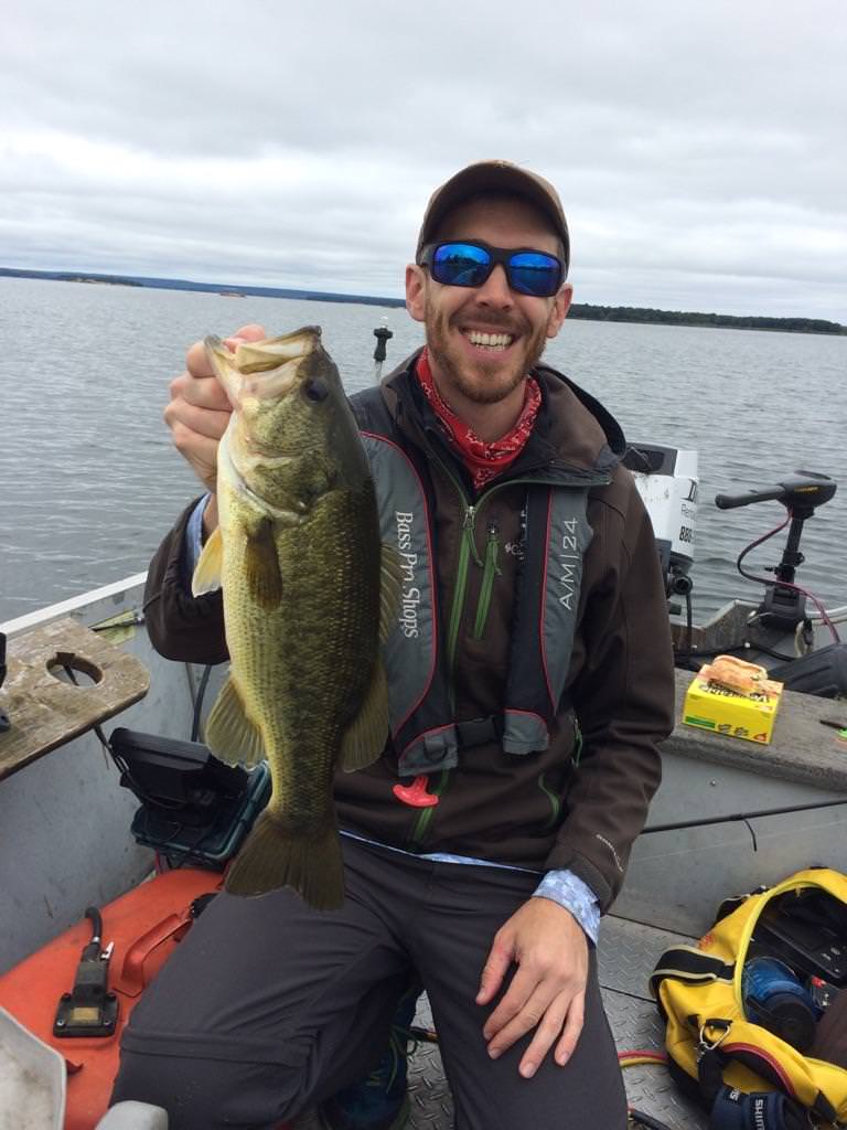 Matthew Randall holding a big Georgian Bay largemouth bass in a boat.