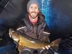 Matthew Randall holding a large walleye on a frozen Bay of Quinte.