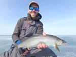 Matthew Randall holding a large Whitefish on a frozen Lake Simcoe.