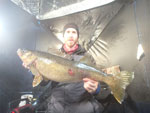 Matthew Randall holding a large walleye on a frozen Bay of Quinte.