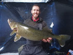 Matthew Randall holding a large walleye on a frozen Bay of Quinte.