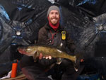 Matthew Randall holding a large walleye on a frozen Bay of Quinte.