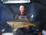 Matthew Randall holding a large walleye on a frozen Bay of Quinte.