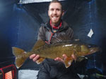 Matthew Randall holding a large walleye on a frozen Bay of Quinte.